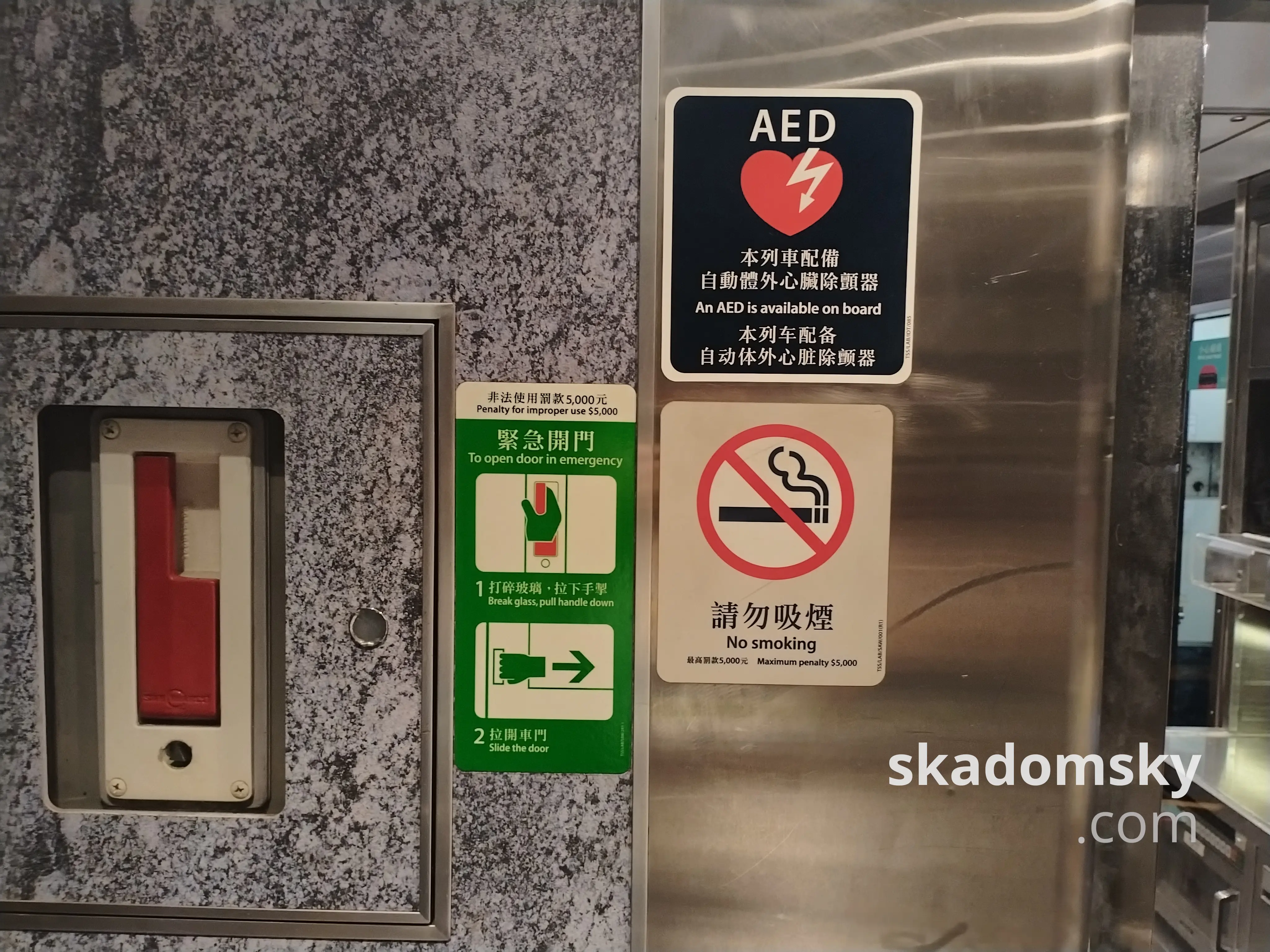车厢标志：“本列车配备自动体外心脏除颤器”，下方是禁止吸烟的提示，左侧是红色的紧急开门把手。