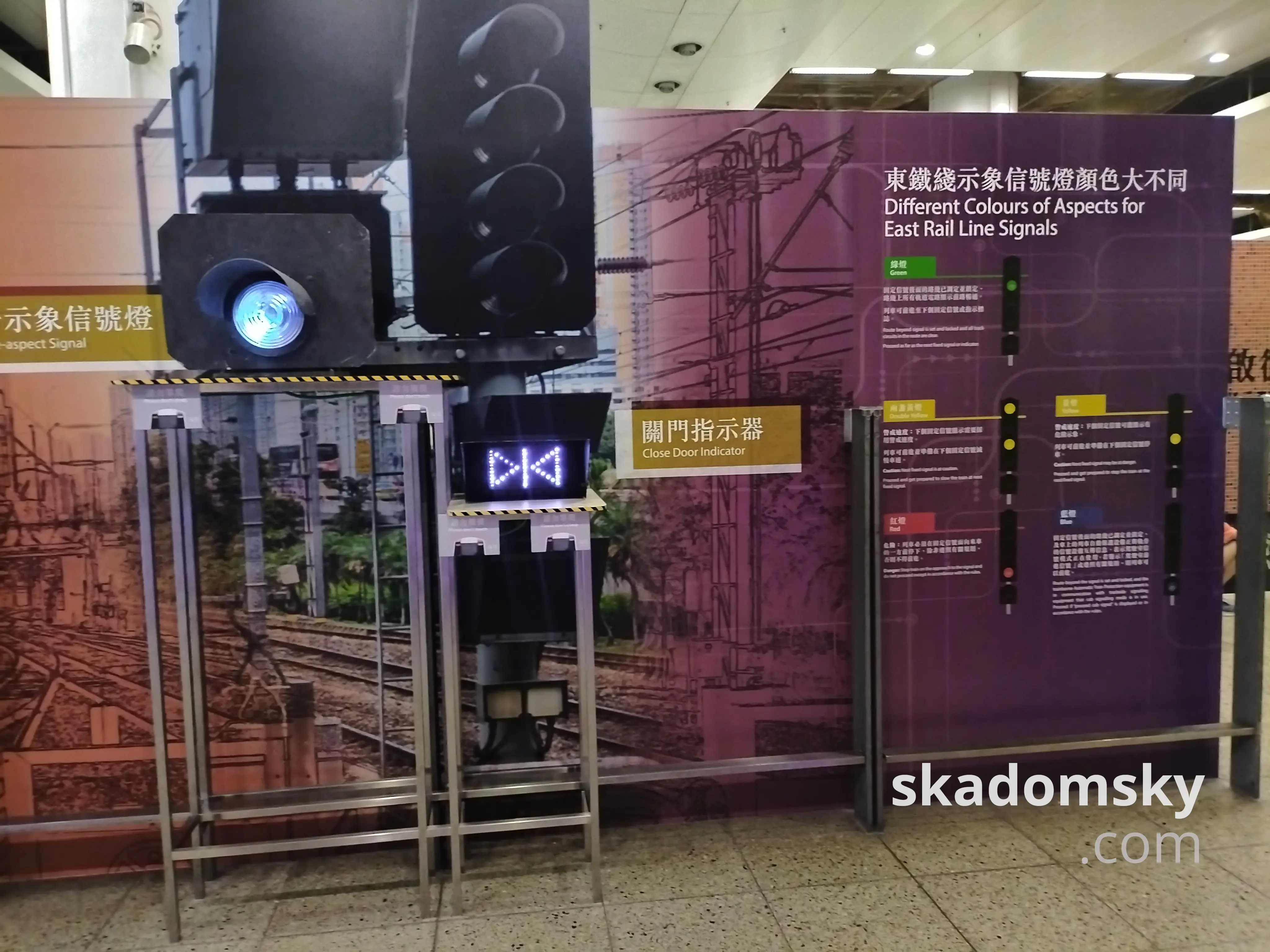 东铁线示象信号灯颜色大不同。展板右侧介绍了四色信号的含义，左侧展示了白色灯光的关门指示器。