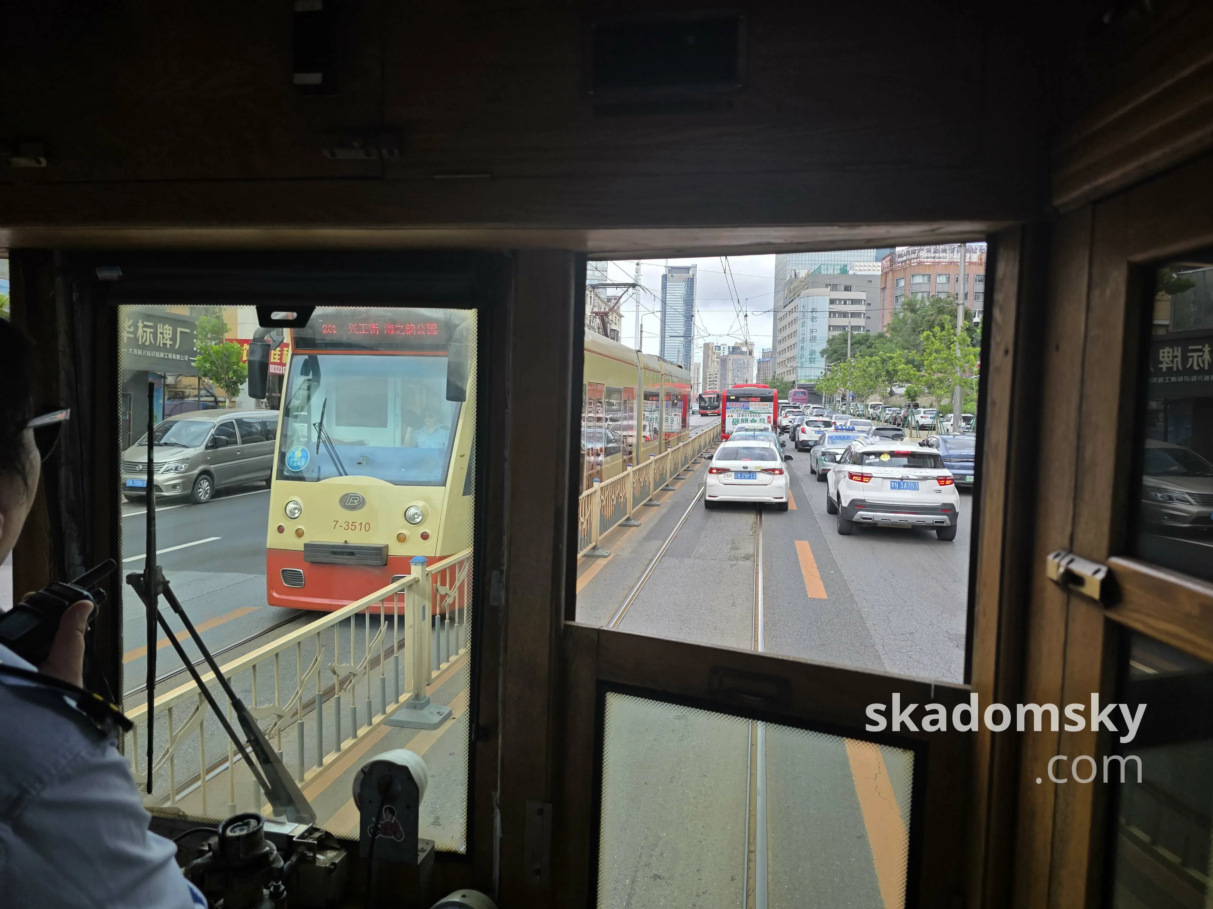 有轨电车经过拥堵路段。对向是一辆三节橙黄色有轨电车。