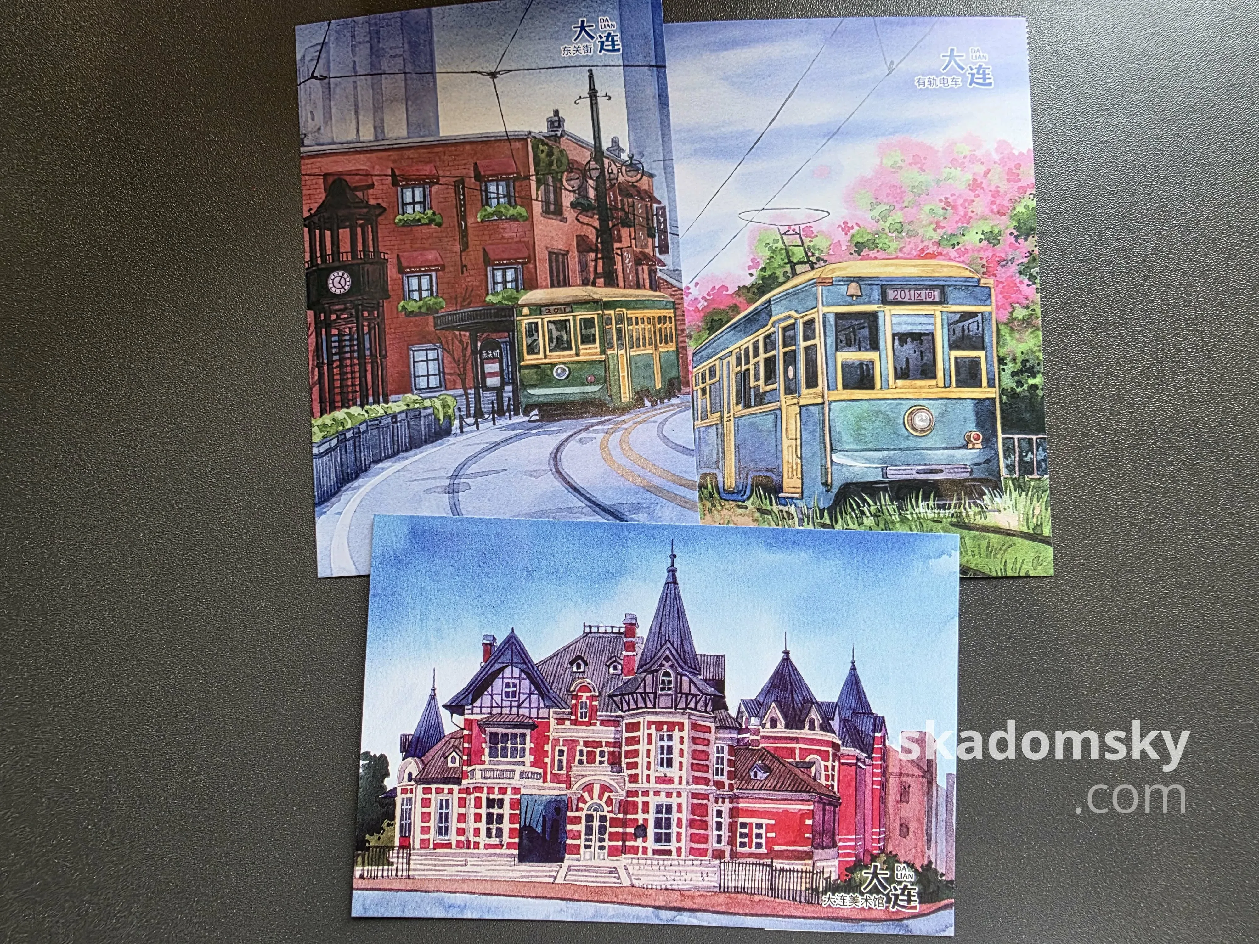 三张明信片。上面两张展示了大连的老式有轨电车,下面一张展示了大连美术馆外景。
