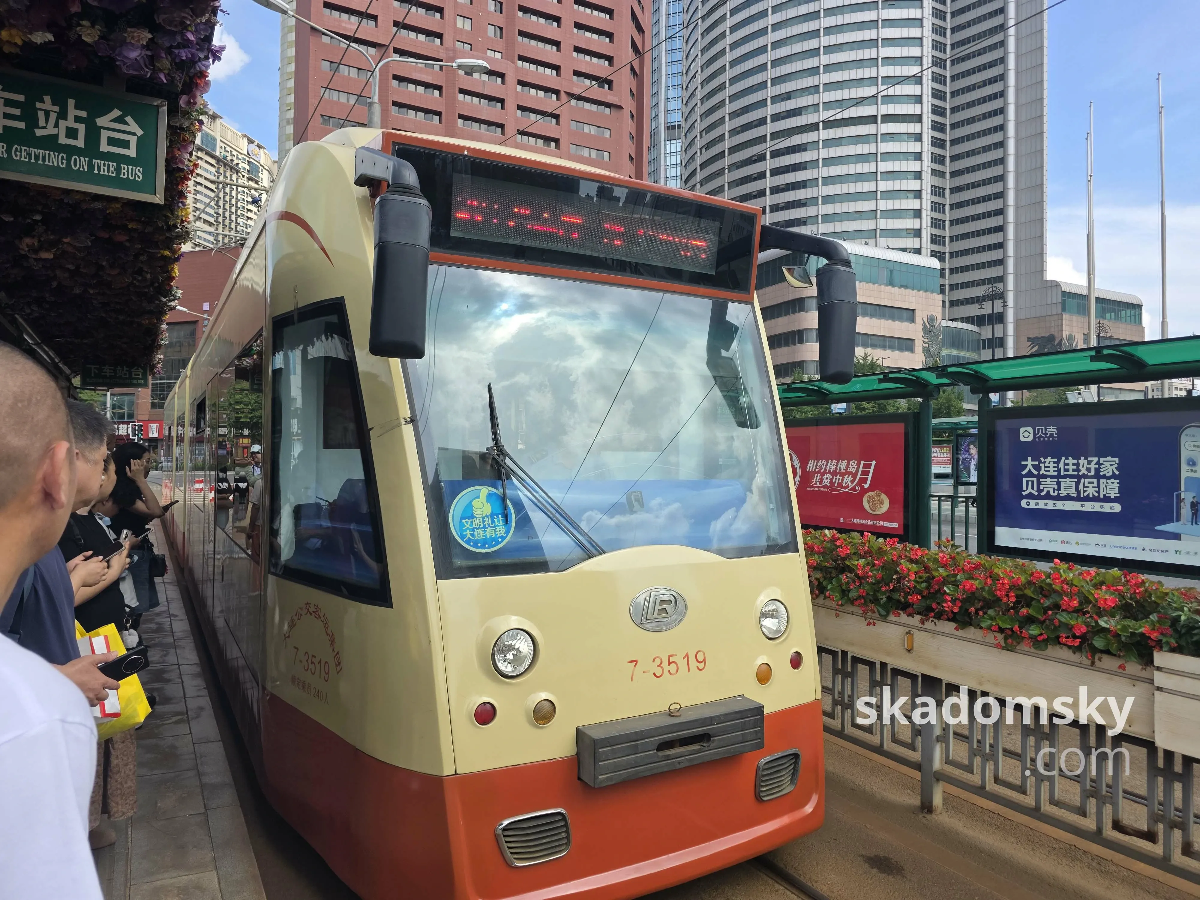 一辆三节黄色的有轨电车停在站台旁边。